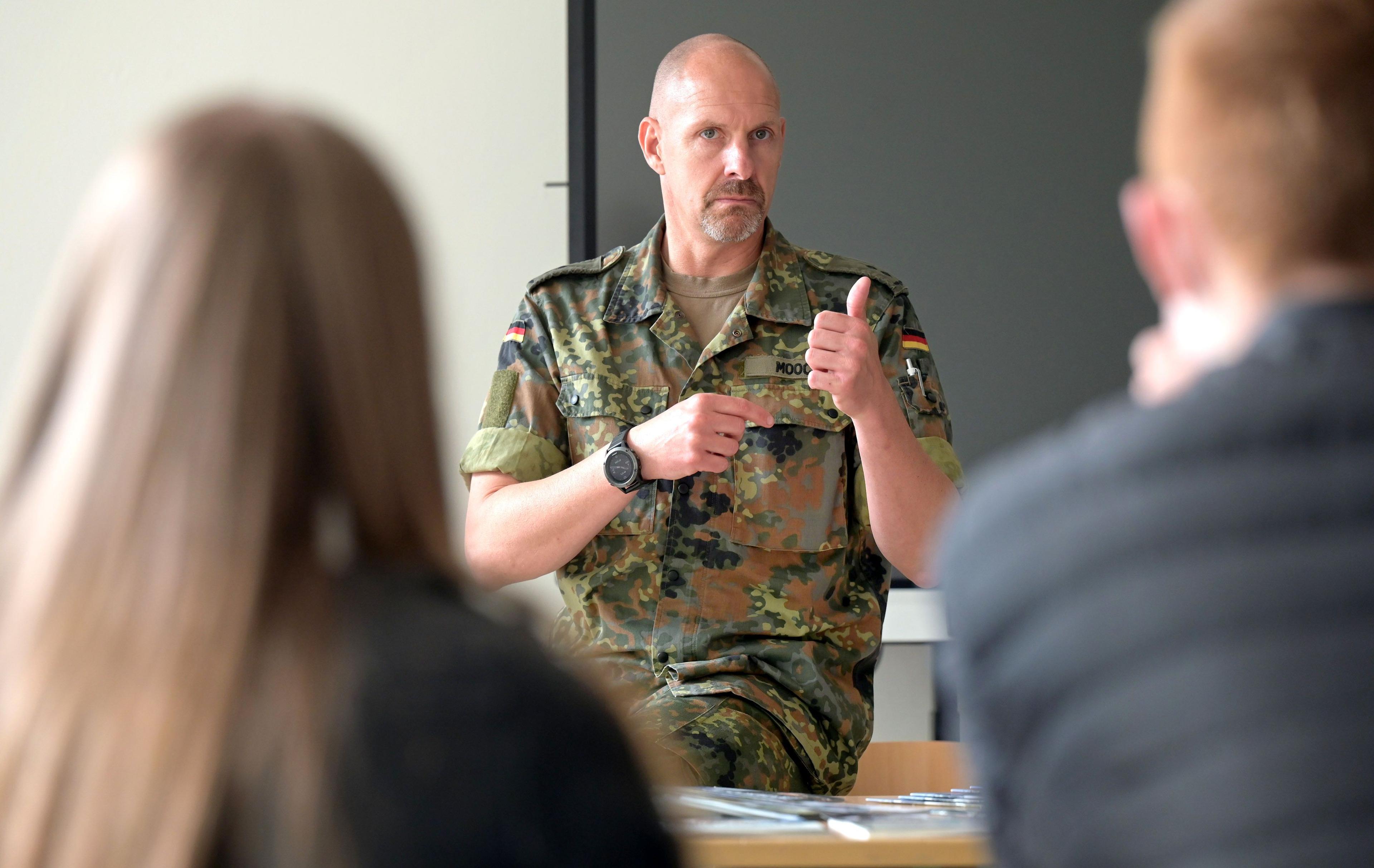 Ein Soldat der Bundeswehr spricht zu einer Schulklasse.